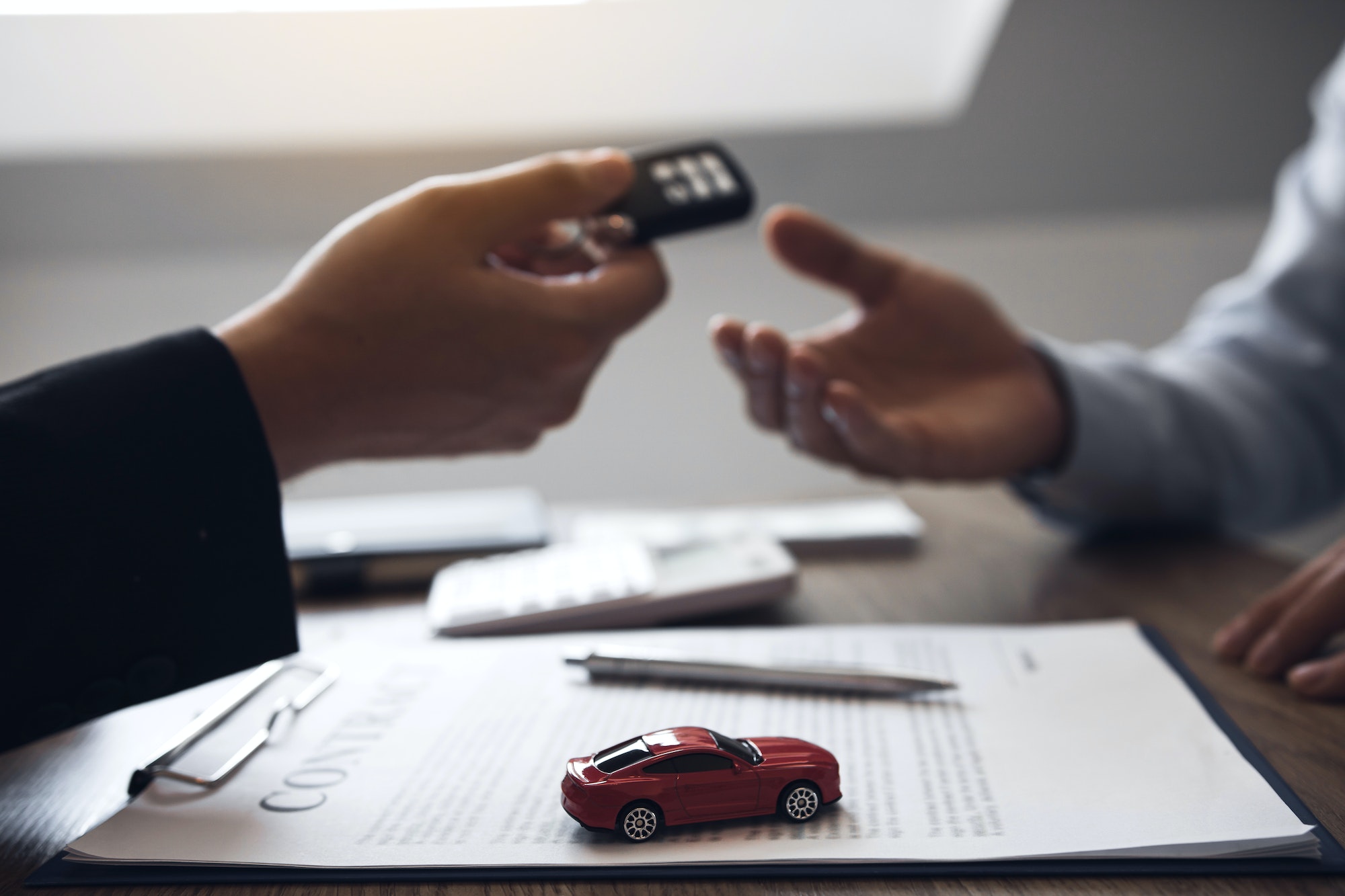 car salesman is presenting the new car keys to the car buyer at the showroom