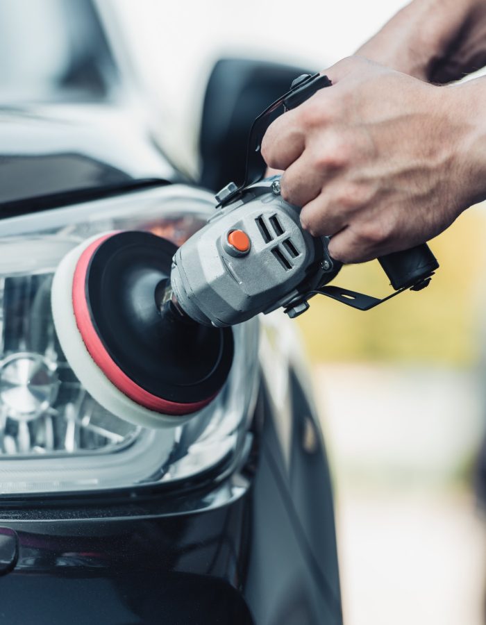 cropped view of car cleaner polishing rear lamp with polish machine